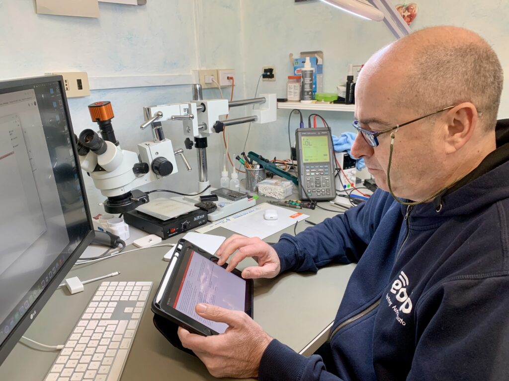 Luca Malin al banco del laboratorio Clinica TV di Ostiglia, con microscopio e oscilloscopio alle spalle