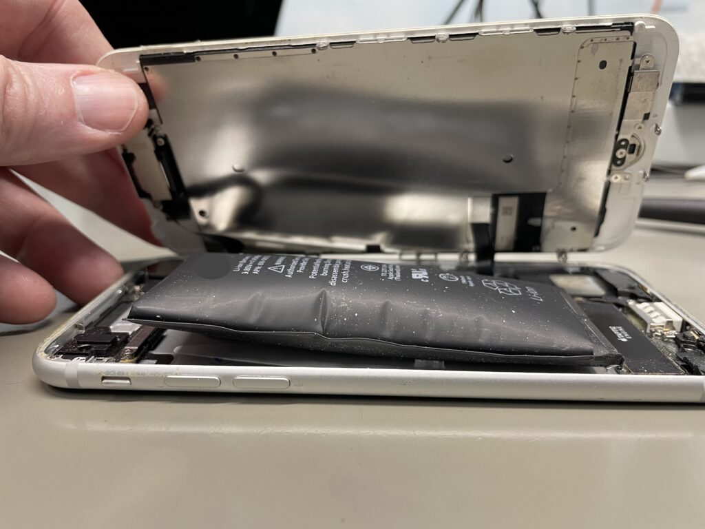 iPhone aperto con batteria rigonfia che solleva il display, prima della sostituzione