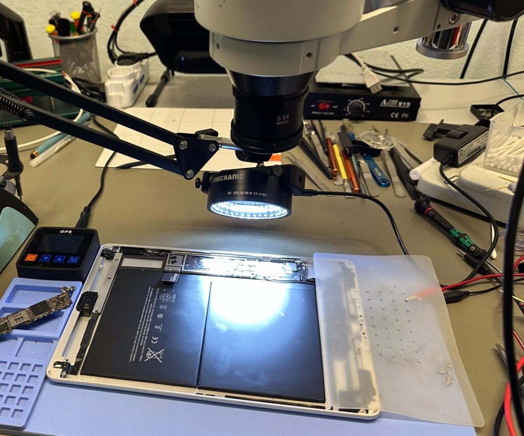 Banco di microelettronica con microscopio, stazione saldante e tablet aperto in riparazione nel laboratorio Clinica TV di Ostiglia