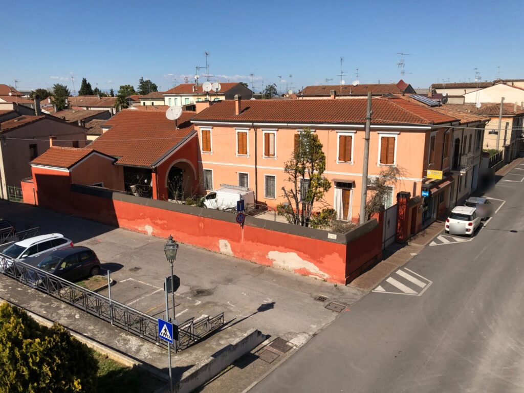 Vista dall'alto della sede Clinica TV in Via Bernardo Tasso 15 a Ostiglia, con l'insegna all'angolo e il parcheggio di fronte